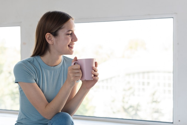Bezpłatne zdjęcie bocznego widoku kobieta trzyma filiżankę kawy