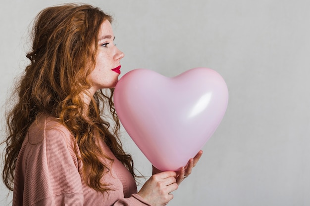 Bocznego widoku ładna kobieta trzyma balon