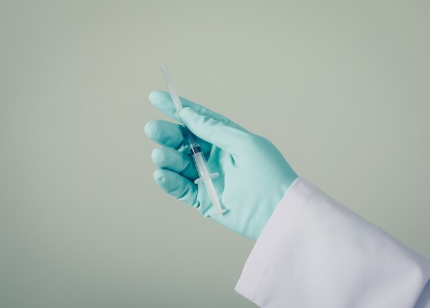 Bocznego widoku lekarka trzyma strzykawkę w jego ręce z rękawiczkami. poziomy
