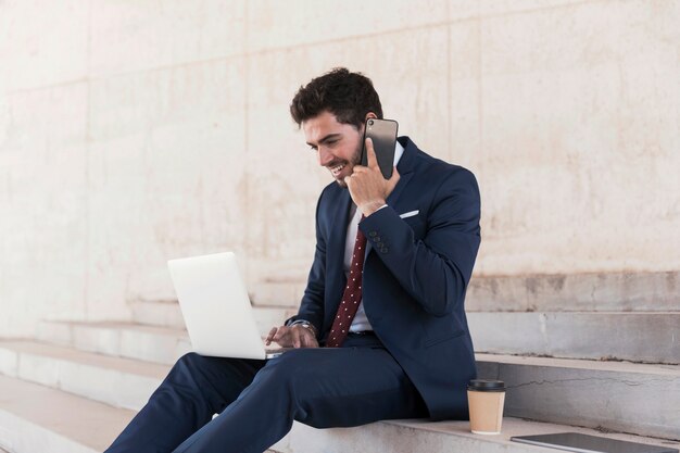 Bocznego widoku prawnik opowiada na telefonie z laptopem