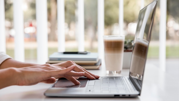 Boczny widok bizneswoman pracuje z laptopem i kawę