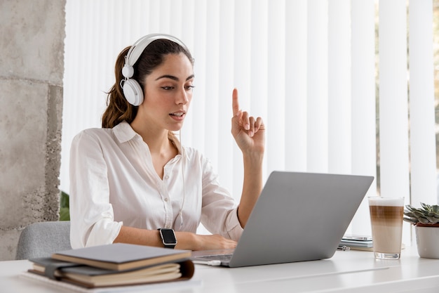Boczny widok bizneswoman pracuje ze słuchawkami i laptopem
