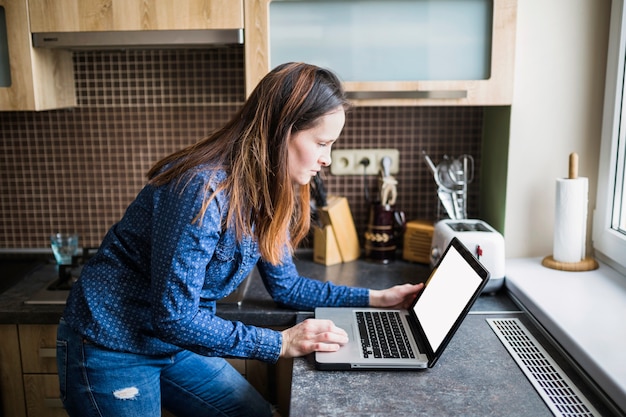Boczny widok kobieta używa laptop w kuchni
