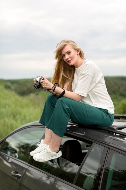 Bezpłatne zdjęcie boczny widok kobieta z kamerą na górze samochodu