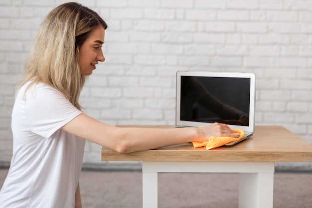 Bezpłatne zdjęcie boczny widok kobiety cleaning laptop z płótnem