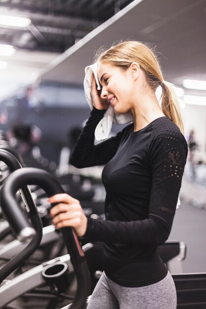 Boczny widok kobiety obcierania pot podczas gdy ćwiczący w gym