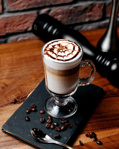 Boczny widok latte macchiato kawa w szkle na drewnianym stole