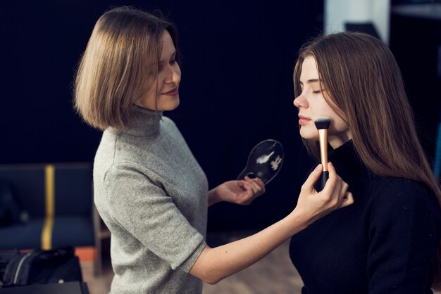 Boczny widok makeup artysta stosuje proszek na modelu