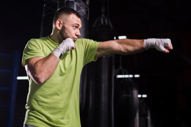 Boczny widok męski boksera miotania poncze w gym