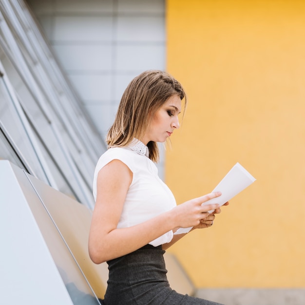 Bezpłatne zdjęcie boczny widok młodzi bizneswomanu czytania dokumenty przy biurowym kampusem