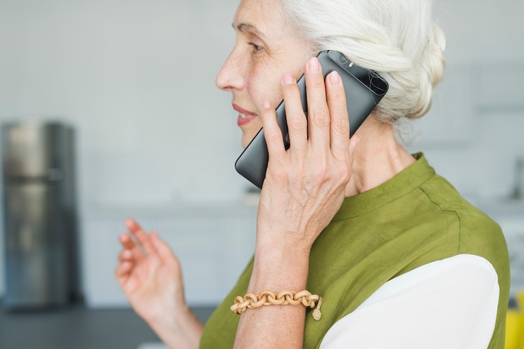 Bezpłatny plik Zdjęcie boczny widok opowiada na telefonie komórkowym starsza kobieta