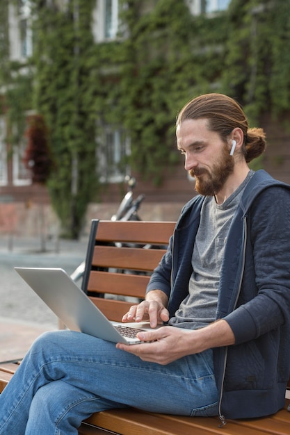 Boczny widok pracuje na laptopie w mieście mężczyzna