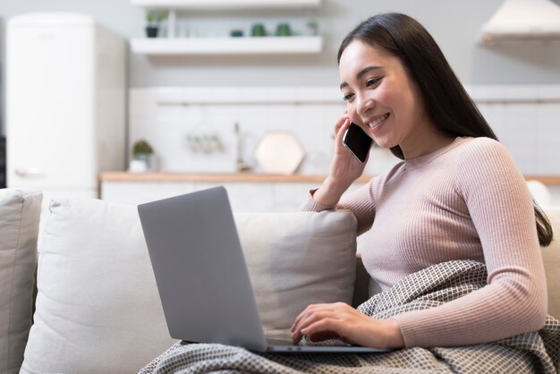 Boczny widok robi zakupy online kobieta podczas gdy opowiadający przez telefon