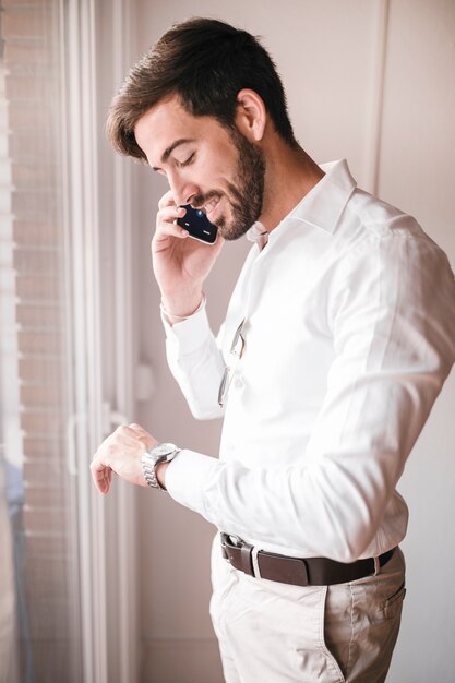 Boczny widok szczęśliwy młody biznesmen opowiada na telefonie komórkowym