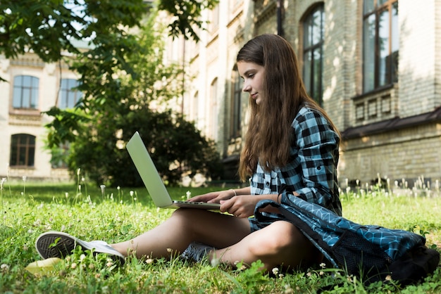 Boczny widok szkolna dziewczyna używa laptop