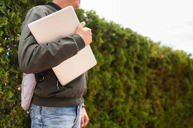 Bezpłatne zdjęcie boczny widok trzyma laptop mężczyzna outdoors