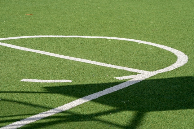 Boisko do koszykówki z zielonym trawiastym boiskiem, sztuczną trawą i białymi liniami