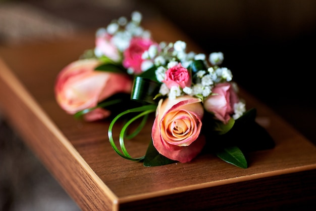Boutonniery z różowych róż i zieleni leżą na stole
