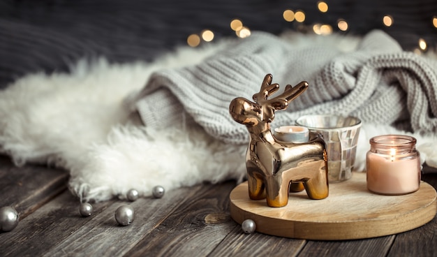 Boże Narodzenie uroczysty tło z zabawkowym jeleniem, niewyraźne tło ze złotymi światłami i świecami, świąteczne tło na drewnianym stole i zimowy sweter na tle