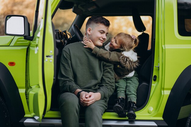 Brat z młodszą siostrą siedzi w zielonym samochodzie
