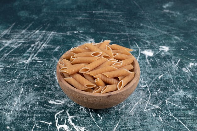 Brązowy surowy makaron penne w drewnianej misce. Wysokiej jakości zdjęcie