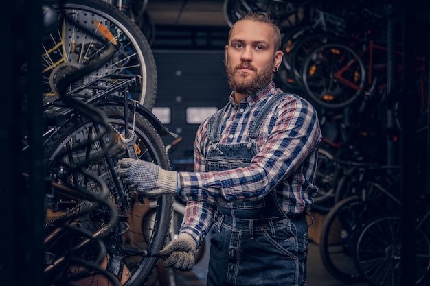 Brodaty mechanik robi instrukcję obsługi koła rowerowego w warsztacie.