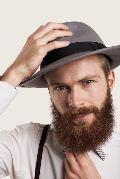 Brodaty mężczyzna portret w stylu hipster w duży szary kapelusz i białą koszulę