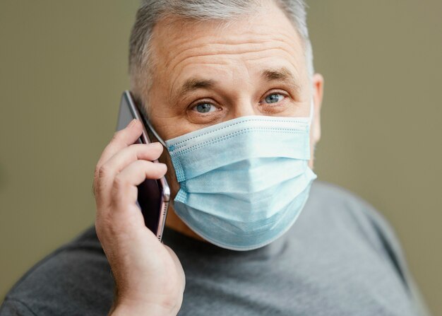 Brodaty mężczyzna z maską chirurgiczną przy użyciu telefonu