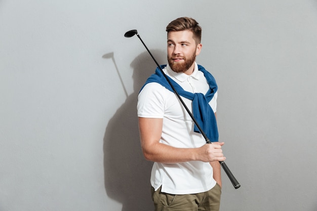 Bezpłatne zdjęcie brodaty uśmiechnięty golfista pozuje z klubem w ręce