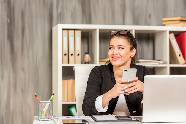 Bezpłatne zdjęcie brunetka bizneswoman używa jej smartphone