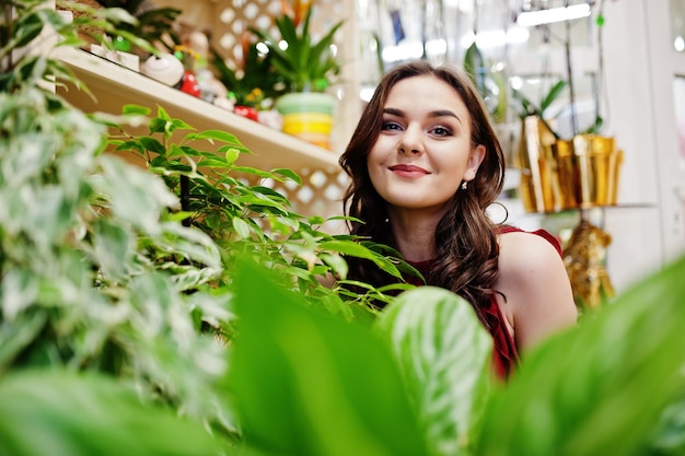 Brunetka dziewczyna w czerwieni kupuje kwiaty w kwiaciarni