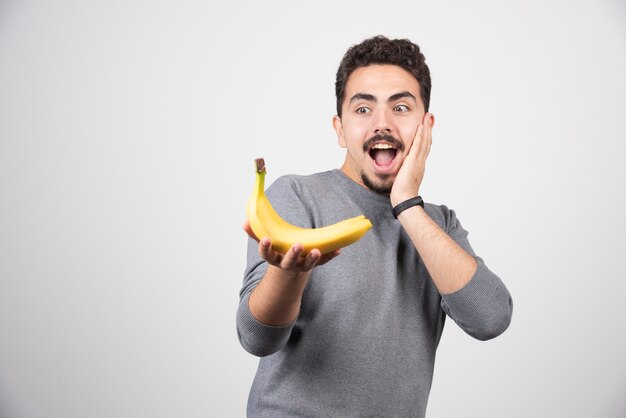 Brunetka mężczyzna patrząc na banana szczęśliwie.