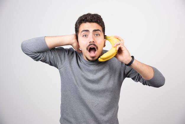 Brunetka mężczyzna trzyma banana jako telefon.