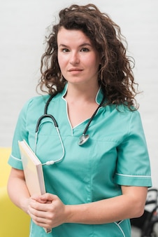 Brunetka młodych kobiet pielęgniarka gospodarstwa książki i stetoskop wokół jej szyi