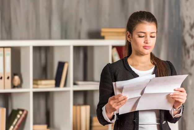 Bezpłatne zdjęcie brunetki bizneswomanu czytanie przy jej biurem