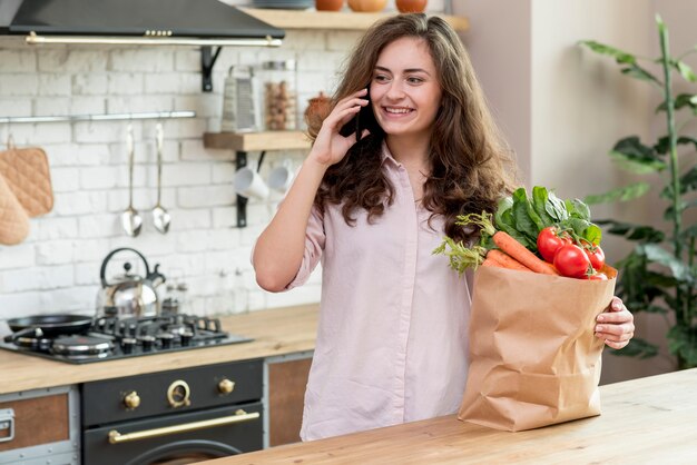 Brunetki kobieta z papierową torbą pełno zdrowy jedzenie