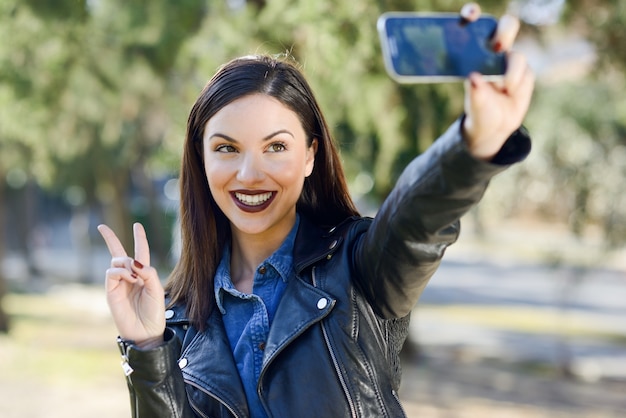 Bezpłatne zdjęcie brunette kobieta biorąc zdjęcie w parku