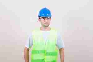 Bezpłatne zdjęcie budowniczy człowiek odwracający wzrok w koszulce, kasku i wyglądający rozsądnie