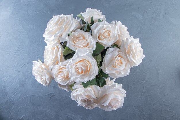 Bukiet białych kwiatów w wiadrze, na białym stole.