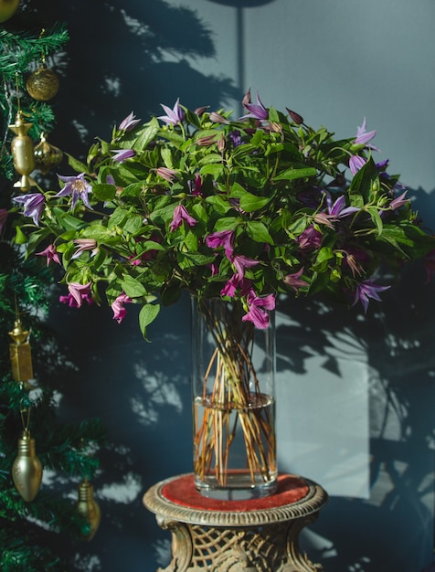 Bukiet fioletowych kwiatów z zielonymi liśćmi w wazonie