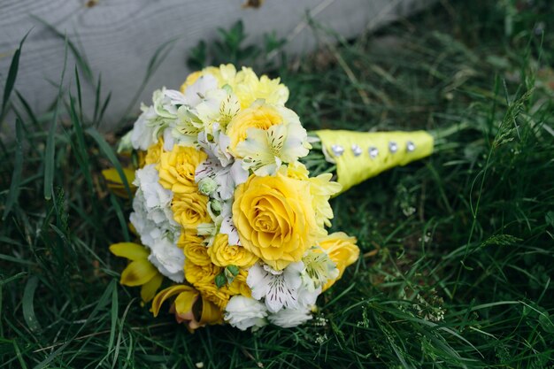 Bukiet ślubny z żółtymi różami leżącymi na trawie