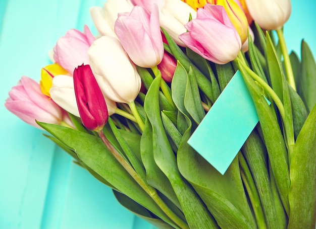 Bukiet świeżych wielokolorowych kwiatów tulipanów na starym niebieskim drewnianym stole