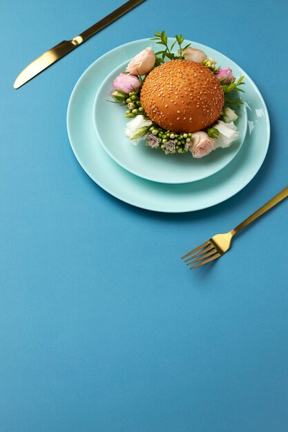 Burger o wysokim kącie z kwiatami na talerzu
