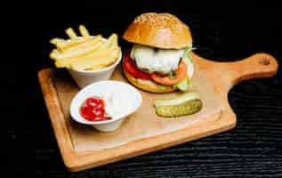 Bezpłatne zdjęcie burger z frytkami, ogórkami i sosem do smażenia