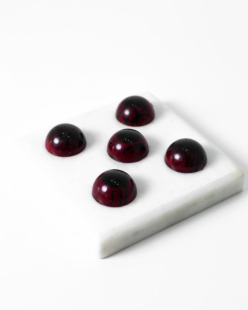 Bezpłatne zdjęcie burgundowe cukierki czekoladowe zaprojektowane smaczne całość na białym tle na białej podłodze
