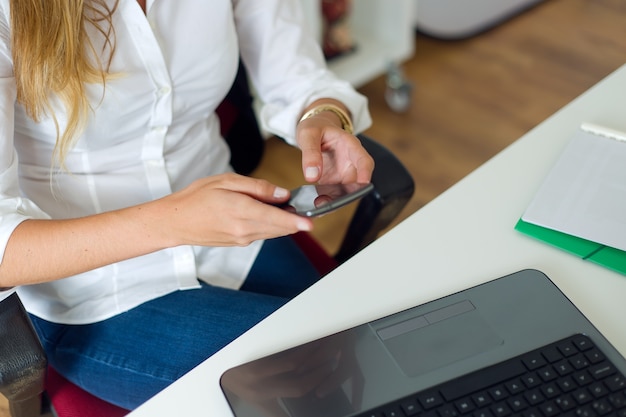 Bezpłatne zdjęcie business woman pracy z telefonu komórkowego w swoim biurze.