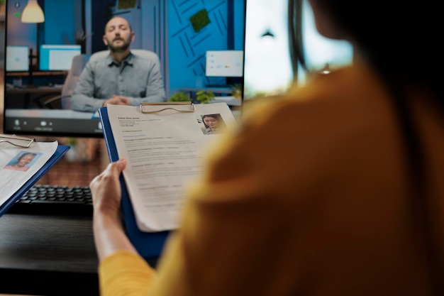 Bezpłatne zdjęcie businesswoman czyta cv freelancera omawiając ofertę zatrudnienia ze zdalnym rekruterem podczas konferencji online spotkanie wideorozmowy w biurze firmy startowej. telekonferencja na ekranie komputera