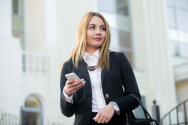 Businesswoman za pomocą swojego smartfona z niewyraźne tło