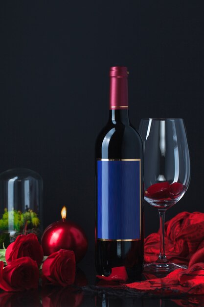 Butelka alkoholu z różami, czara, świeczką i szalikiem