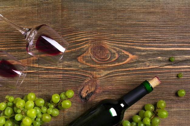 Butelka czerwonego wina winogrona i szklanki nad drewnianym blatem z miejscem na kopię